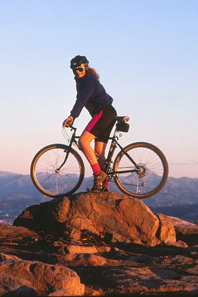 eyes wide open Patty Mooney poses on rock pinnacle Cowles Mountain mission trails with her mountain bike