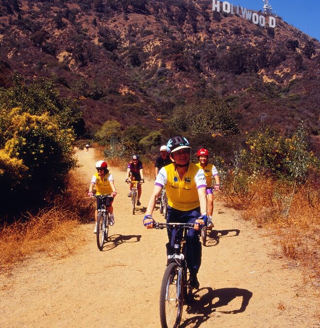 James Hong, April, and Susan enjoy a thrilling bike ride along the trail beneath the famous Hollywood sign. They exude joy and adventure as they pedal together, surrounded by the scenic beauty of the Hollywood hills