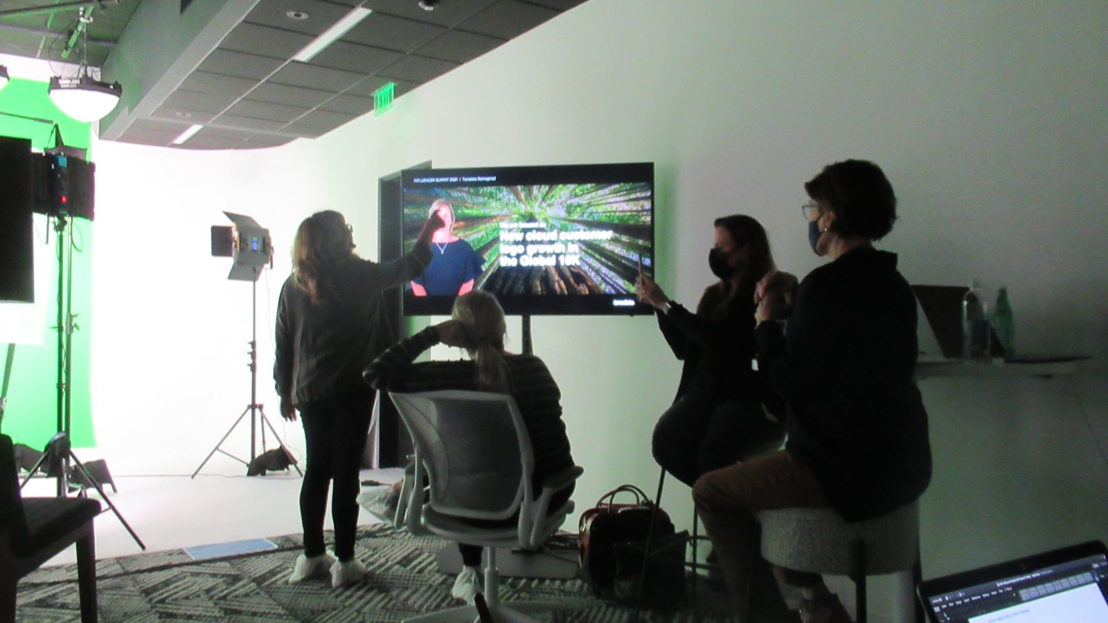 Client team reviewing composited green-screen footage on a large monitor during a video shoot
