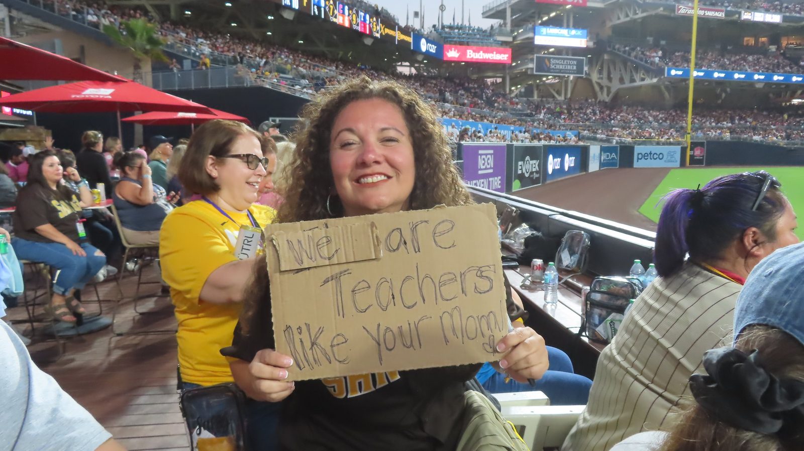 Teacher holding a handmade sign at a Rise Up Foundation game day for teachers at Petco Park, San Diego